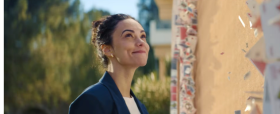 Cette image est une capture d'écran de la campagne publicitaire de LA BANQUE POSTALE. On y voit une conseillère sourire après avoir ajouté la dernière carte (reprenant le logo de la BANQUE POSTALE) au château de carte. Cela provoque la disparition de la structure au profit d'une maison.